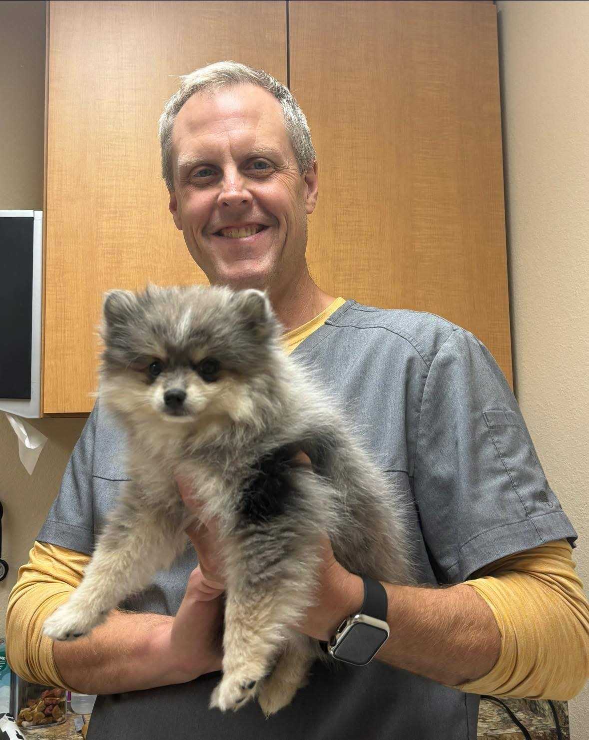 man proudly holding pomeranian dog